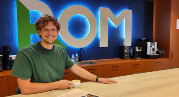 foto van een man met een koffie kopje met de letter POM achter zich